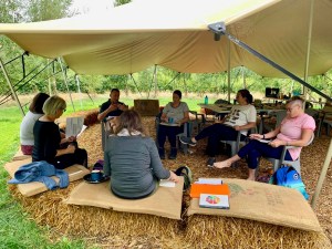 group of people outside under a canopy taking part in a personal resilience course